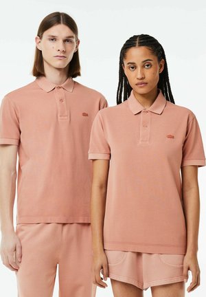 Camisas polo rosas hechas de una mezcla de poliéster, con mangas cortas, una tapeta de tres botones y un logo bordado en el pecho.