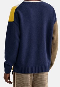 Maglione a maglia con sezioni in blu navy, giallo e verde oliva. Tessuto testurizzato con polsini e orlo a coste, collo rotondo con dettagli a righe.