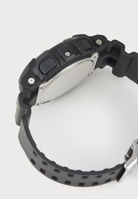 Black rubber watch with a textured bezel, metal accents, and a silver case back. Features a perforated strap for breathability.