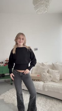 Svart kort tröja med ribbad fåll kombinerad med grå utsvängda jeans med blommig brodyr vid bensluten. Mjuk, texturerad tyg.