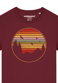 Burgunderfarbenes T-Shirt mit einem kreisförmigen Grafikdesign, das schichtweise Sonnenuntergangsstreifen in Orange, Gelb und Grün zeigt, sowie Silhouetten von Bäumen und Vögeln.