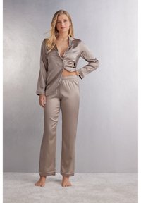 Luxe beige pyjama set met lange mouwen en een notched collar, met een knooptop en broek met elastische tailleband en contrast piping.