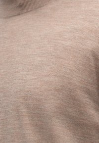 Világosbarna garbópulóver, kötött textúrával, testhezálló szabással, puha anyagból. Bordás nyakkal és sima felülettel rendelkezik.