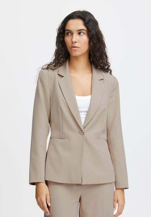 Blazer beige realizzato in tessuto liscio. Presenta una chiusura con un solo bottone, rever a vista e tasche laterali. Design sartoriale e aderente con maniche lunghe.