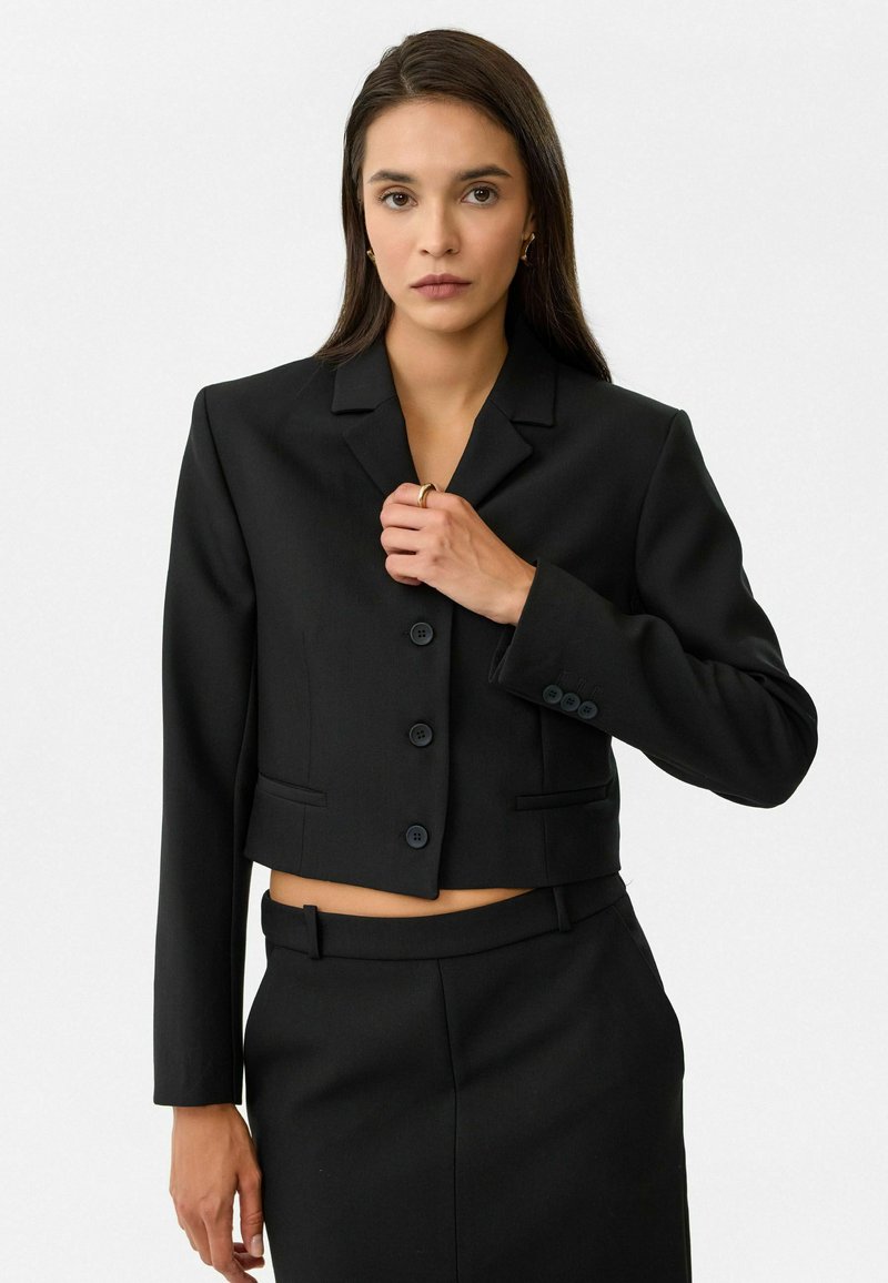 Zwarte gecropte blazer met notch-lapels, zes knopen en twee voorke pockets. Gemaakt van een soepele stof, met een getailleerde pasvorm en lange mouwen.