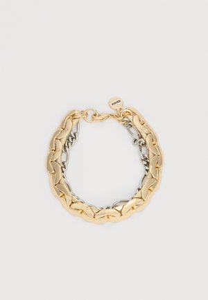 Kuld- ja hõbedast seotud kettidega käevõru, millel on homaar lukustus ja väike ümmargune silt, millele on graveeritud "DKNY", valgel taustal.