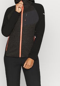 Kapuzensweatshirt mit strukturiertem dunkelgrauem Körper und schwarzen Ärmeln. Verfügt über neongelbe Reißverschluss- und Taschenakzente. Hergestellt aus weichem, flexiblem Material.