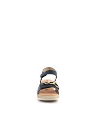 Sandalo in pelle blu navy con una fascia larga, dettagli in metallo dorato e suola beige. Design open-toe con una cinghia malleolare di supporto.