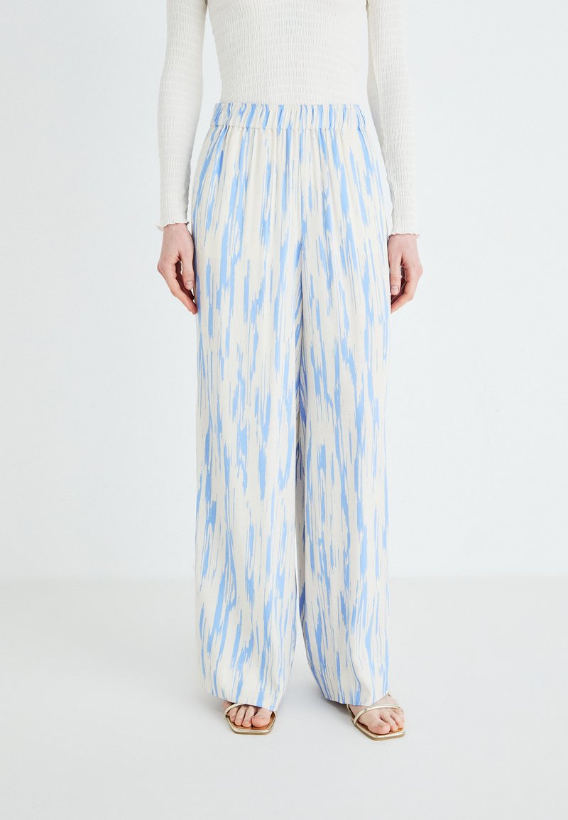 Wide-leg pants in a light cream color with blue abstract patterns. Features an elastic waistband. Made from a lightweight fabric.