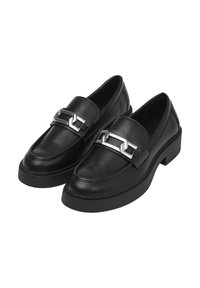 Mocassini in pelle nera con una piattaforma bassa, caratterizzati da un dettaglio a catena argentata sulla parte frontale e una cucitura discreta lungo i bordi.