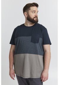 Kortermet t-skjorte med horisontale fargeblokker i marineblått, grått og taupe. Inkluderer en lomme på forsiden og en rund hals.