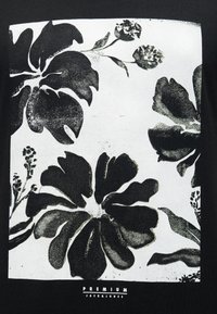 Ασπρόμαυρο φλοράλ σχέδιο με μεγάλα αφηρημένα λουλούδια και φύλλα, περιβαλλόμενο από ένα λευκό τετράγωνο σε μαύρο φόντο.