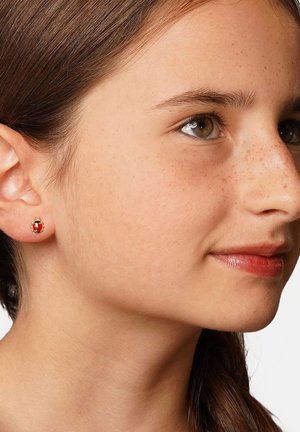 Goldene Steckerohrringe mit einem roten und schwarzen Emaille-Design, runder Form und glatter Oberfläche, getragen von einer hellhäutigen Person.