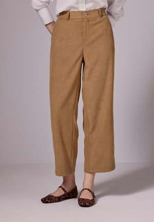 Tanskleurige wijde broeken met een zachte textuur, voorzakken en een knoopsluiting. Gecombineerd met bruine leeuwinnenprint flats.