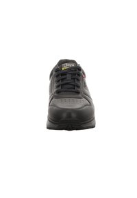 Zapatilla atlética negra con parte superior de cuero perforado, puntera redonda y suela de goma. Presenta cordones negros y la marca Joya en la lengua.