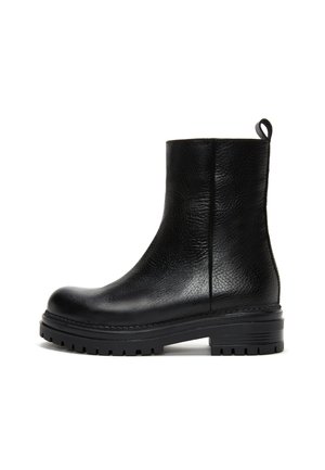 Bottine noire en cuir avec surface texturée, semelle crantée épaisse, bout arrondi et languette à l’arrière.