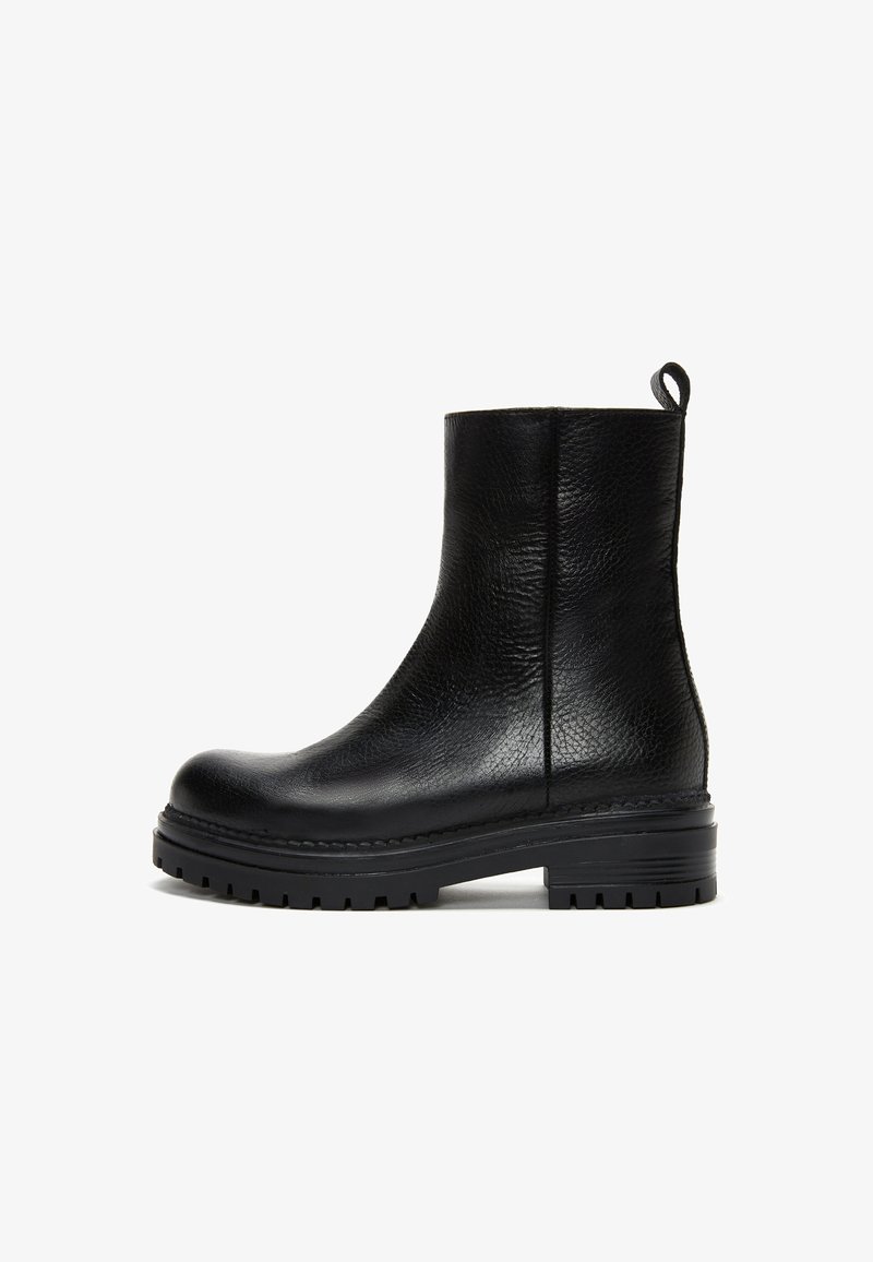Bottine noire en cuir avec surface texturée, semelle crantée épaisse, bout arrondi et languette à l’arrière.