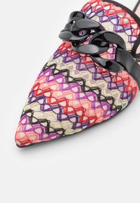 Scarpa a punta colorata caratterizzata da un design a rete con fili rossi, viola e neri. Accentuata da una catena nera e rifiniture in pelle.