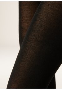 Černé punčocháče s hladkou pletenou texturou. Mají poloprůhledný vzhled a zdůrazňují tvar nohou. Jsou měkké na dotek.