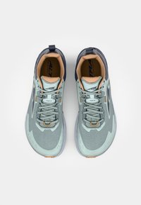 Chaussures de trail en vert menthe pâle et marine, avec une tige texturée, un col rembourré et une semelle en caoutchouc dotée de motifs de traction.
