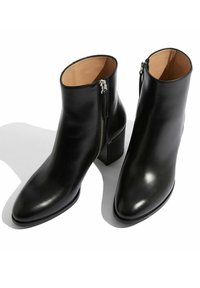 Czarne skórzane botki za kostkę o gładkiej fakturze, z zamkiem błyskawicznym po boku i słupkowym obcasem dla większej stabilności. Klasyczny design.