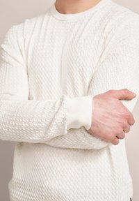 Weißer Strickpullover mit strukturiertem Muster, gerippten Bündchen und klassischem Rundhalsausschnitt, der ein leichtes, atmungsaktives Design demonstriert.