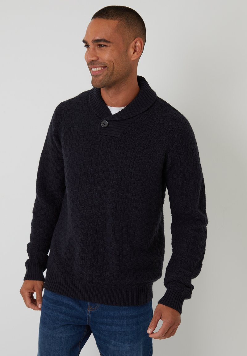Maglione di lana blu navy scuro con colletto a scialle, dettaglio con bottoni frontali e motivo a quadri testurizzato. Abbinato a jeans blu.
