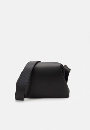 Bolsa de couro preto com uma textura suave, design curvado e uma única alça de ombro ajustável. Possui um fecho com zíper na parte superior.