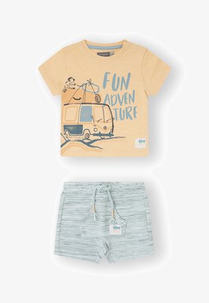 Camiseta de algodón amarilla con el texto "DIVERSION EN AVENTURA" y gráfico de una furgoneta camper, combinada con pantalones cortos rayados grises con cintura ajustable.