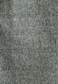 Textil mit Fischgrätmuster in Schwarz und Weiß, mit einer strukturierten Oberfläche aus gewebtem Stoff.