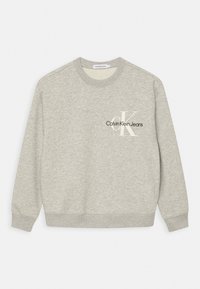 Sudadera gris hecha de tela suave. Presenta un cuello redondo, puños y dobladillo acanalados, con "Calvin Klein Jeans" y un logotipo impresos en el pecho.
