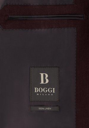 Wnętrze ciemnej tkaninowej kurtki z czarną metką białym napisem "B Boggi Milano" oraz mniejszą metką poniżej z napisem "100% len."