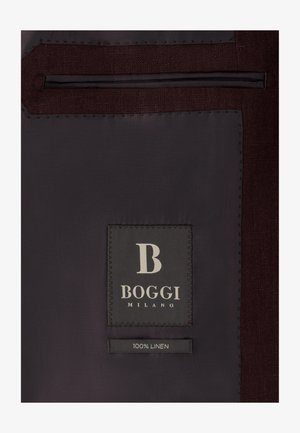 Wnętrze ciemnej tkaninowej kurtki z czarną metką białym napisem "B Boggi Milano" oraz mniejszą metką poniżej z napisem "100% len."