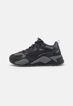 Black athletic sneakers featuring mesh and textile upper with gray accents, a chunky sole, and distinctive design lines.
