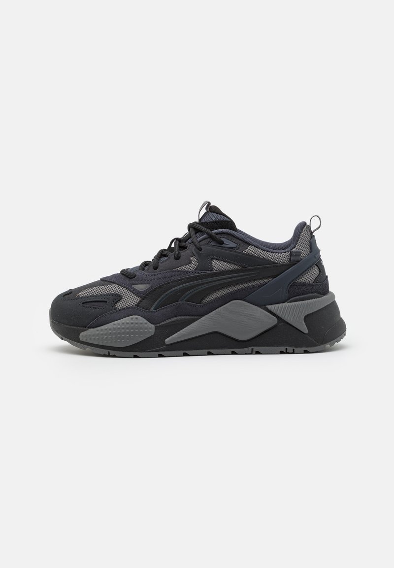 Sneakers atléticos pretos com parte superior em malha e têxtil com acentos cinzas, sola robusta e linhas de design distintas.