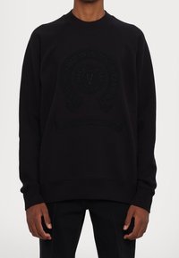 Schwarzer Pullover mit einem strukturierten Logo auf der Vorderseite, rundem Ausschnitt sowie gerippten Bündchen und Saum. Hergestellt aus einem weichen, atmungsaktiven Stoff.