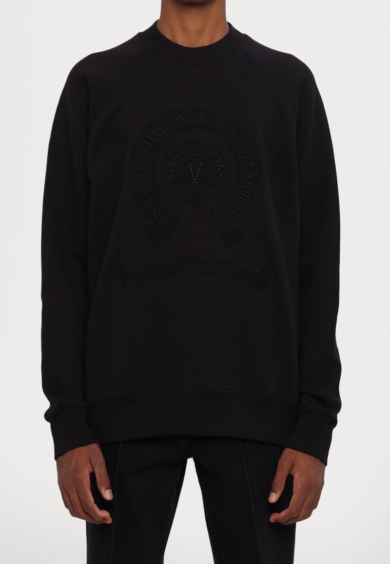 Schwarzer Pullover mit einem strukturierten Logo auf der Vorderseite, rundem Ausschnitt sowie gerippten Bündchen und Saum. Hergestellt aus einem weichen, atmungsaktiven Stoff.