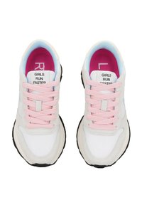 Zapatillas deportivas blancas con cordones rosas, suela negra y detalles en azul claro. El texto interior dice "LAS CHICAS CORREN MÁS RÁPIDO". Material suave, diseño redondeado.
