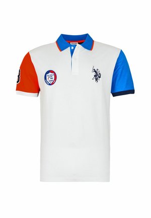 Biele polo tričko s červeným ľavým rukávom, modrým pravým rukávom a golierom, s logom U.S. Polo Assn. na hrudi a odznakom na ľavej strane.