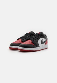 Sneaker nere, rosse e bianche con chiusura in lacci; parte superiore in pelle, punta perforata e suola in gomma con cuciture visibili e accenti del logo.