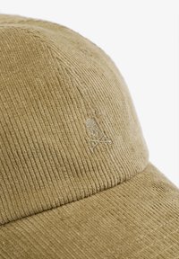Gorra de pana beige con textura de canalé vertical y un sutil detalle bordado de una calavera y huesos cruzados en la parte frontal.