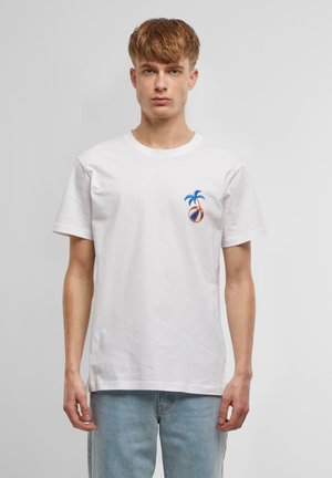 Hvit bomulls t-skjorte med et fargerikt brodert design av to blå palmer og en oransje og blå ball på venstre brystområde.