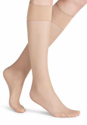 Bas nylons couleur chair avec une texture lisse, des bandes larges et douces en haut, présentant un design ouvert au niveau des orteils pour une meilleure respirabilité.