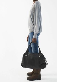 Zwarte leren handtas met een gestructureerde afwerking, voorzien van zilveren hardwareaccenten en ritsen. De tas heeft ronde handvatten en een ruime ontwerp.
