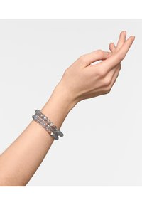 Geknoopte armband om een pols, met multi-kleurige semi-doorzichtige kralen in grijs, roze en iriserende tinten, met een gladde textuur.