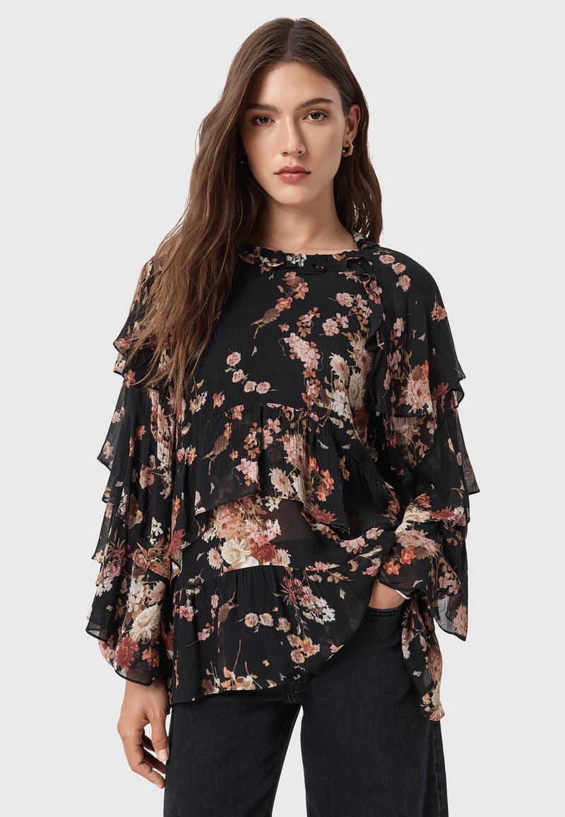 Blusa nera floreale con rouches a strati, realizzata in tessuto leggero. Presenta un colletto rotondo e vari motivi floreali nei colori rosa, arancione e crema.