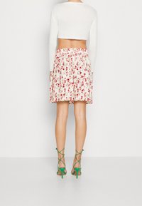 Vit långärmad crop-top ådd kombinerad med en veckad blommig kjol i vitt, rosa och grönt. Gröna sandaler med hög klack och remmar fulländar looken.