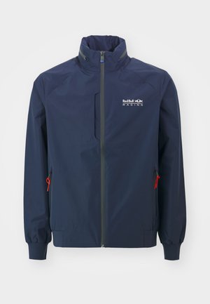Navy blue lightweight jacket with a high collar, front zipper, and two side pockets featuring red drawstrings and gray accents. Logo on chest.