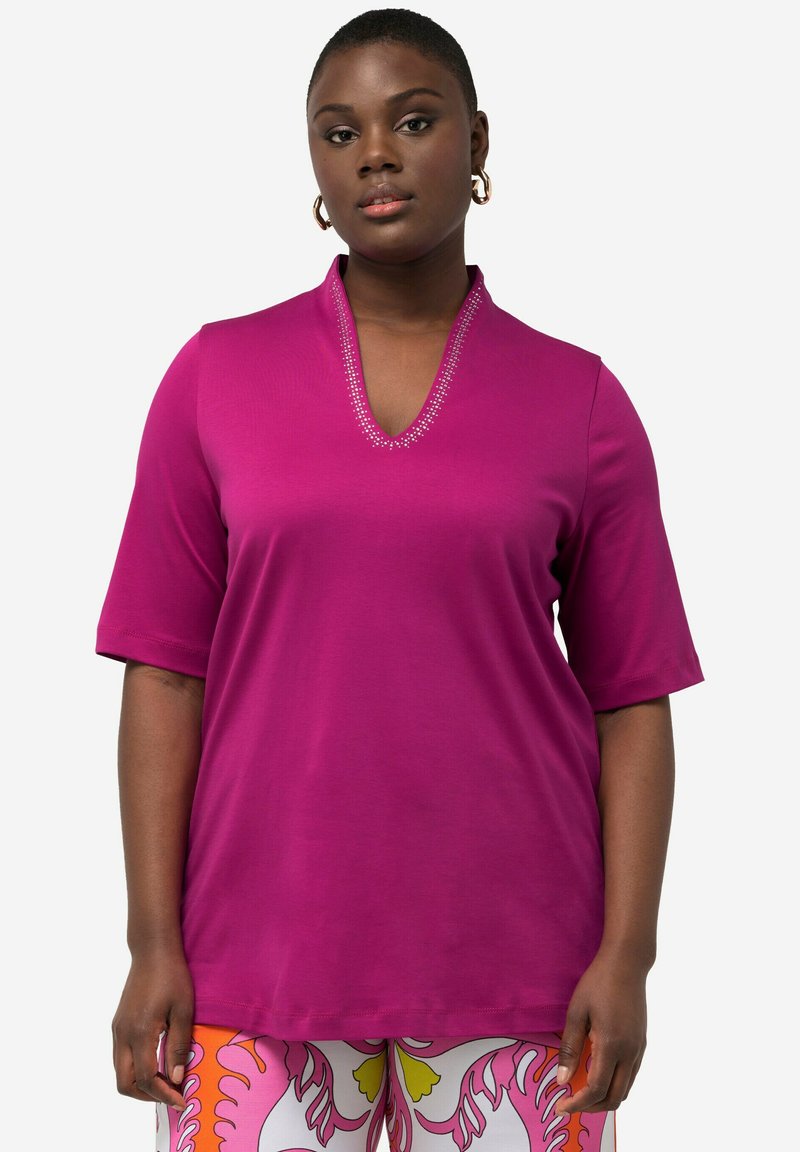 Fuchsia T-shirt met korte mouwen en een V-hals, versierd met zilveren studs. Gemaakt van een soepel stof, met een ontspannen pasvorm en subtiele draping.
