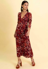 Langes Blumenkleid mit tiefem V-Ausschnitt, langen Ärmeln und tailliertem Oberteil. Besitzt ein rot-rosa Blumenmuster auf dunklem Hintergrund.